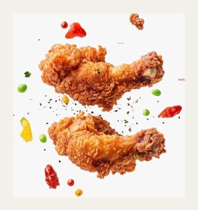 Two crispy fried chicken drumsticks with scattered seasoning